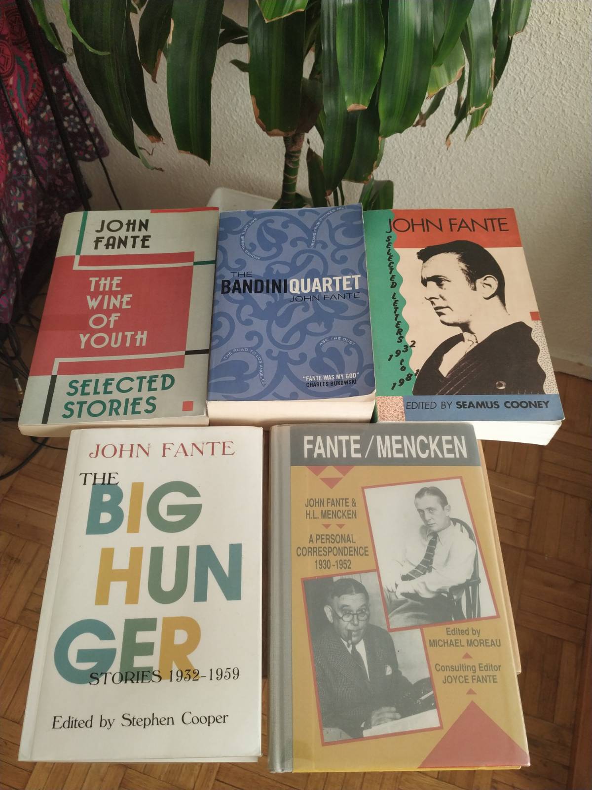 Se ven los cinco libros de John Fante: The Wine of Youth; The Bandini Quartet; Selected Letters, The Big Hungers Stories y A personal Correspondence (John Fante y H.L. Mencken). Se ve una planta de fondo.